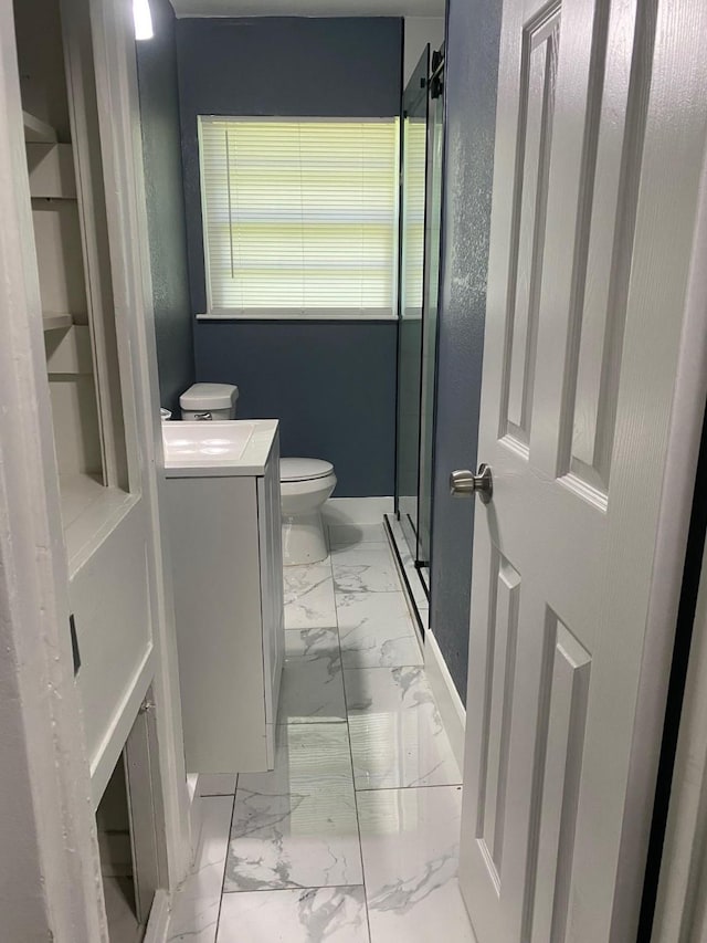 bathroom with a shower stall, vanity, toilet, marble finish floor, and baseboards