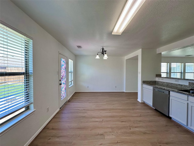 kitchen featuring a textured ceiling, visible vents, light wood-style floors, a notable chandelier, and dishwasher