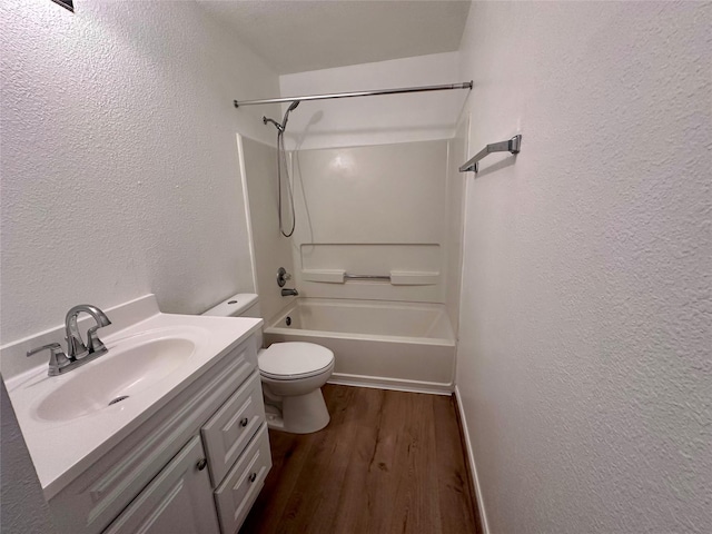 full bath with toilet, wood finished floors, washtub / shower combination, a textured wall, and vanity