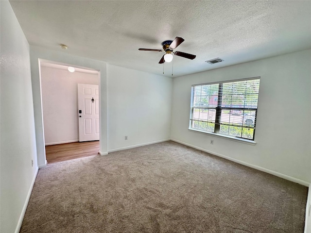 carpeted spare room with baseboards, visible vents, a textured ceiling, and ceiling fan