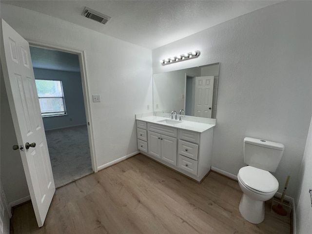 bathroom with wood finished floors, visible vents, toilet, and vanity