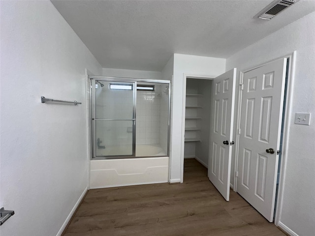 full bathroom featuring baseboards, wood finished floors, visible vents, and shower / bath combination with glass door