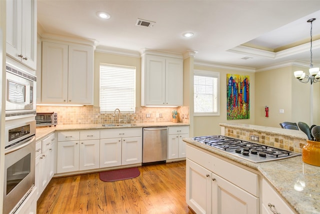 kitchen with visible vents, crown molding, a sink, backsplash, and stainless steel appliances