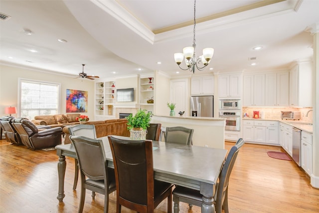 dining space with visible vents, ornamental molding, light wood-style flooring, and ceiling fan with notable chandelier