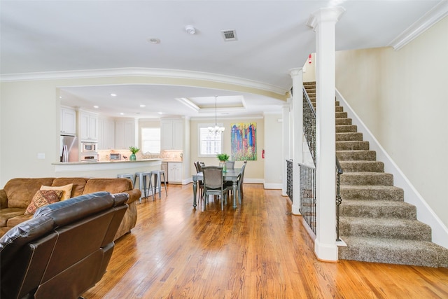 dining space with crown molding, visible vents, light wood finished floors, and stairway