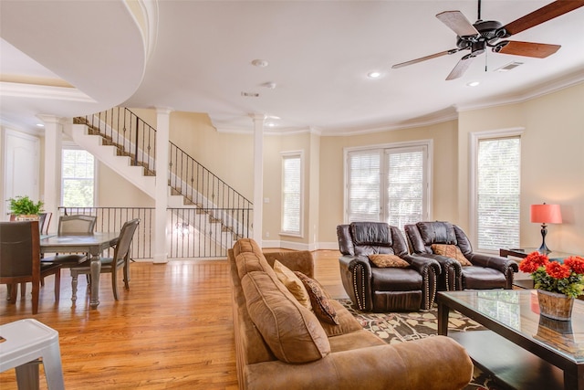 living room featuring light wood-style floors, ornamental molding, a ceiling fan, and decorative columns