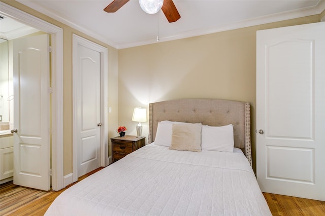 bedroom featuring crown molding, a ceiling fan, connected bathroom, and light wood finished floors