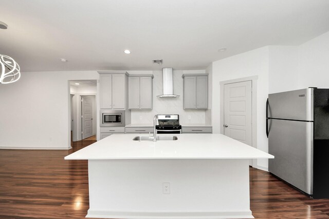2906 Chase Cross Ln, Houston, TX 77047 - kitchen with stainless steel appliances, wall chimney exhaust hood, gray cabinets, dark wood-type flooring, and an island with sink