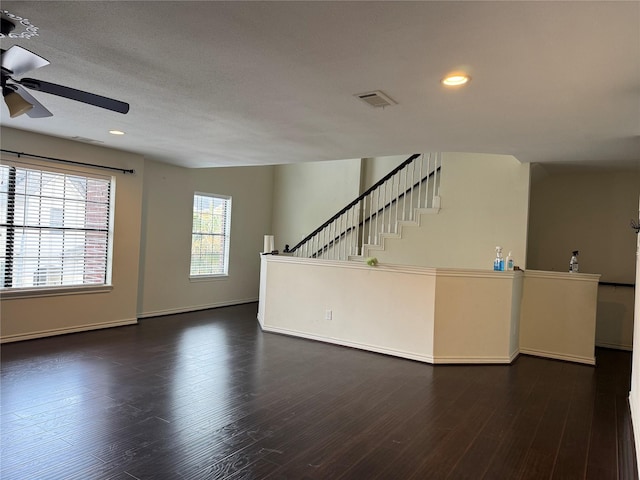 unfurnished living room featuring stairway, visible vents, ceiling fan, and wood finished floors