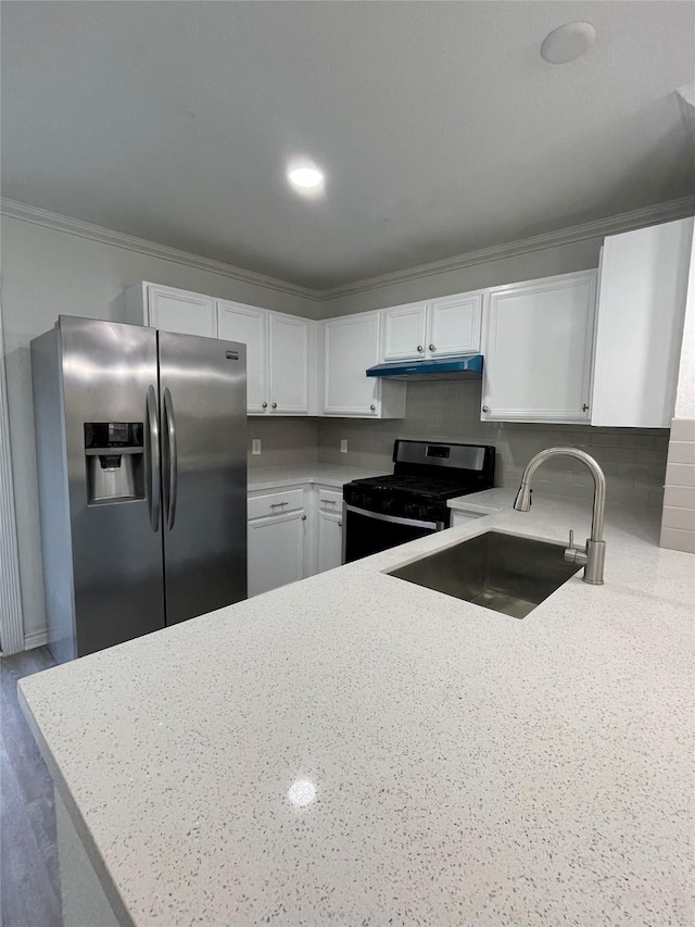kitchen with white cabinets, stainless steel fridge, a sink, light stone countertops, and gas range oven