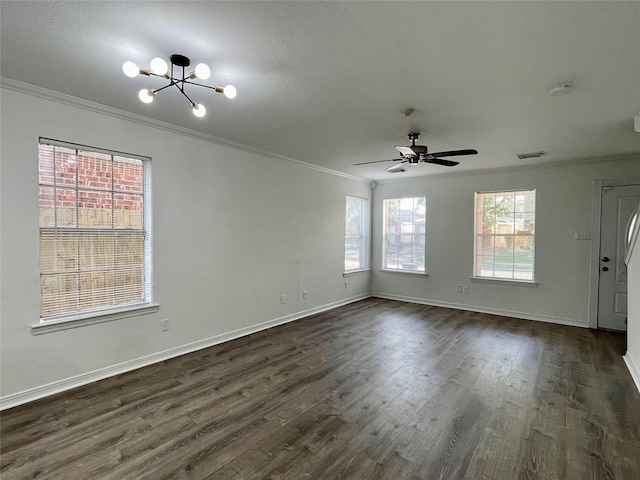 empty room with baseboards, ornamental molding, dark wood-type flooring, visible vents, and ceiling fan with notable chandelier