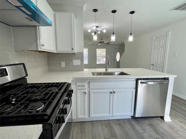 kitchen featuring wall chimney exhaust hood, a sink, light wood-type flooring, stainless steel appliances, and decorative backsplash