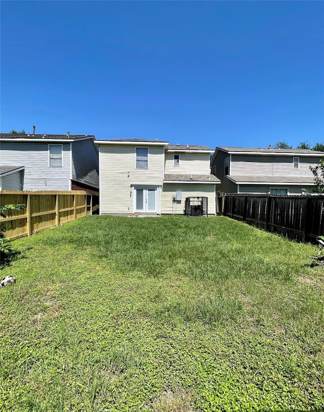 rear view of property featuring a yard and a fenced backyard