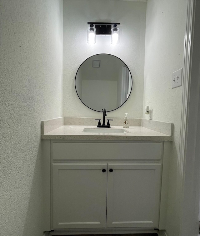 bathroom with vanity and a textured wall
