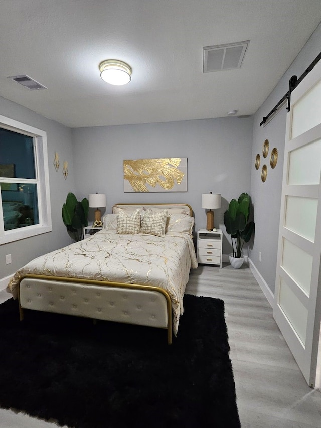 3241 Reeves St, Houston, TX 77004 - bedroom with a barn door, light wood-type flooring, and baseboards