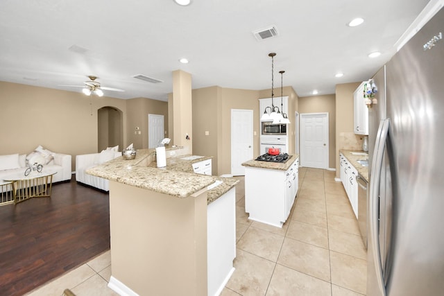 kitchen with stainless steel appliances, a center island, light tile patterned floors, white cabinetry, and a sink