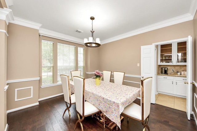 dining area featuring a chandelier, dark wood-type flooring, crown molding, and baseboards