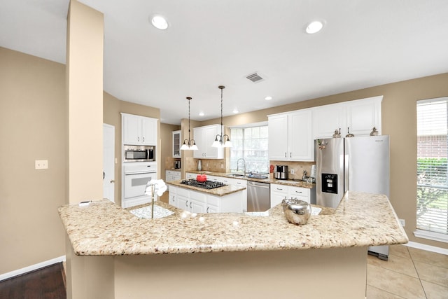 kitchen featuring stainless steel appliances, a spacious island, a sink, baseboards, and white cabinetry