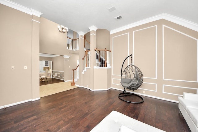 unfurnished living room featuring a decorative wall, hardwood / wood-style floors, stairway, a chandelier, and ornamental molding