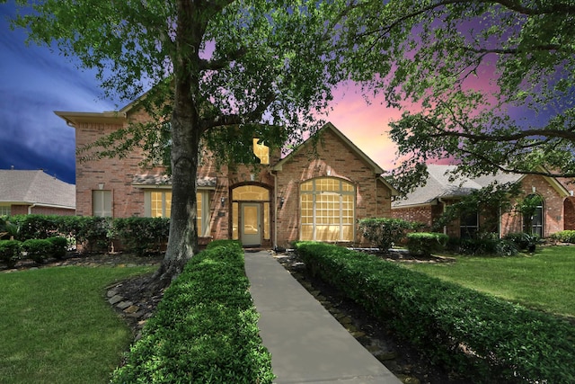 view of front facade featuring brick siding and a yard
