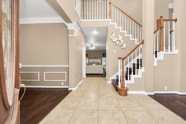 entryway with stairway, tile patterned floors, ornamental molding, ceiling fan, and baseboards