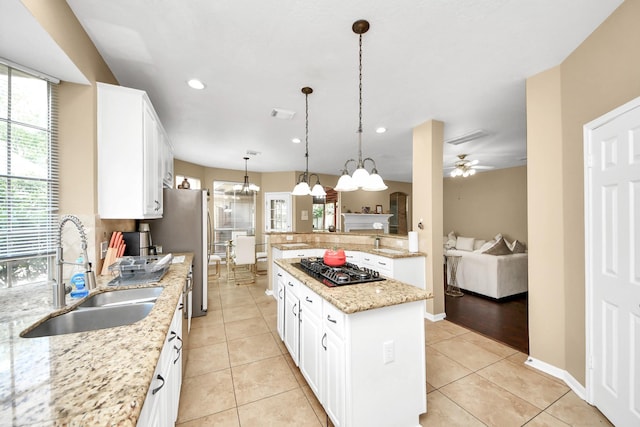 kitchen featuring a sink, black gas stovetop, light tile patterned flooring, light stone countertops, and freestanding refrigerator