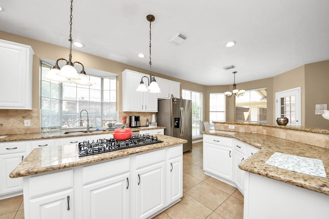 kitchen featuring stainless steel refrigerator with ice dispenser, black gas stovetop, a sink, a chandelier, and a center island
