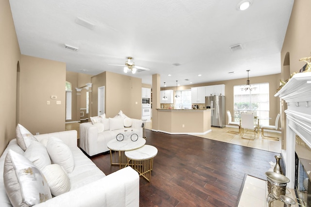 living room featuring light wood-style floors, a ceiling fan, recessed lighting, a chandelier, and baseboards