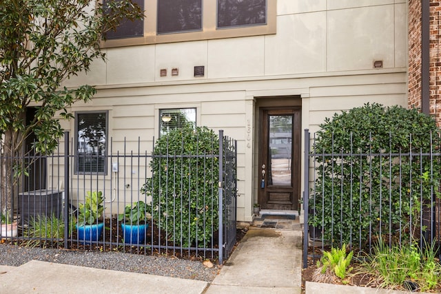 property entrance with a gate, fence, and cooling unit
