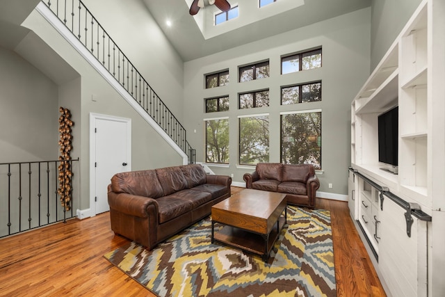 living area featuring a healthy amount of sunlight, a high ceiling, ceiling fan, and wood finished floors