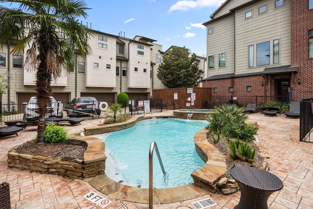 pool with a patio, a community hot tub, and fence