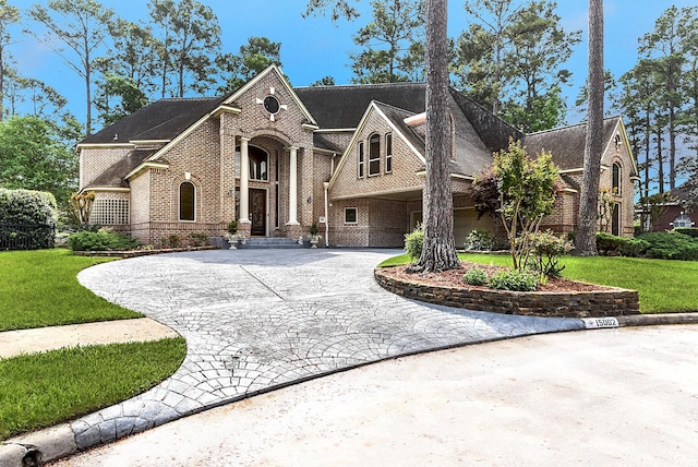 view of front of house featuring a front yard, brick siding, a shingled roof, and curved driveway