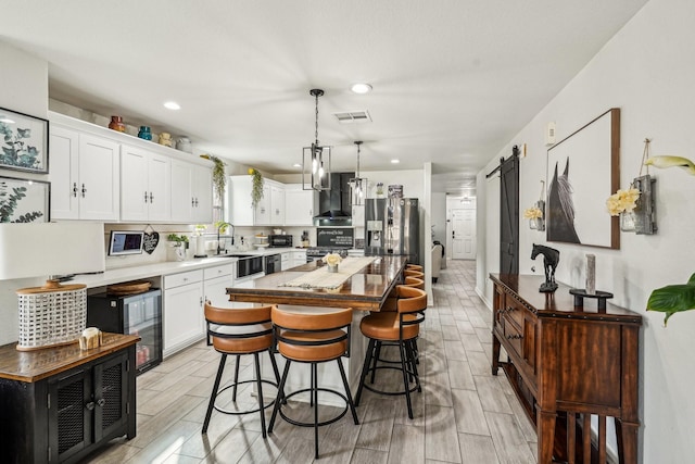 8010 Clover Leaf Dr, Rosenberg, TX 77469 - kitchen with visible vents, a sink, wall chimney exhaust hood, appliances with stainless steel finishes, and white cabinetry