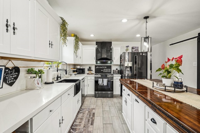 8010 Clover Leaf Dr, Rosenberg, TX 77469 - kitchen with a barn door, wall chimney range hood, a sink, black appliances, and white cabinetry