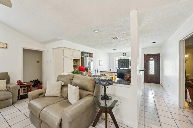 5347 Inwood Dr, Katy, TX 77493 - living area with a textured ceiling, light tile patterned floors, vaulted ceiling, and visible vents
