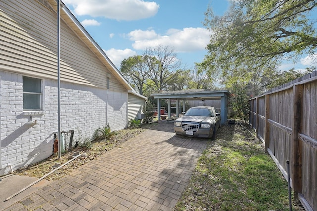 5347 Inwood Dr, Katy, TX 77493 - exterior space featuring a carport, brick siding, decorative driveway, and fence