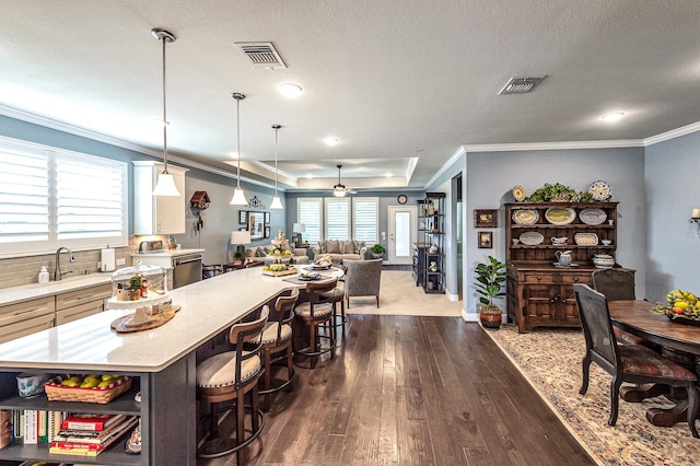 kitchen with visible vents, open floor plan, wood finished floors, and a kitchen bar