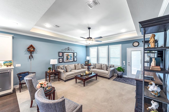 living room featuring ornamental molding, a tray ceiling, and visible vents