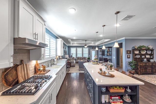 kitchen featuring visible vents, a sink, open floor plan, white cabinetry, and stainless steel gas stovetop