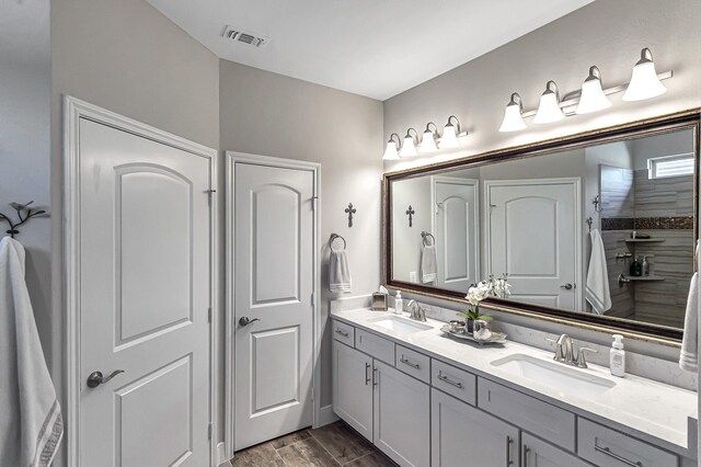 full bath with double vanity, visible vents, a sink, and wood finish floors
