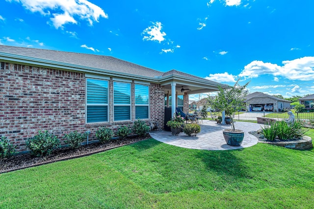 back of house with ceiling fan, a yard, a patio area, fence, and brick siding