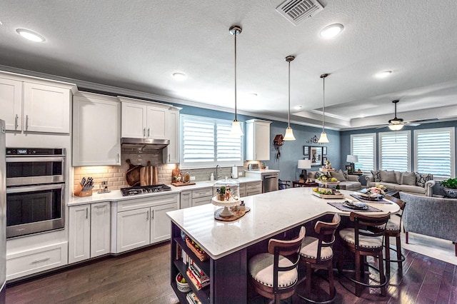 kitchen with dark wood-style flooring, open floor plan, a kitchen bar, and stainless steel appliances