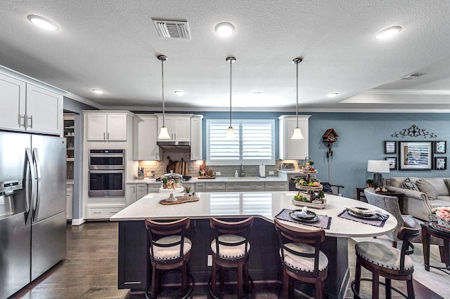 kitchen with ornamental molding, light countertops, visible vents, appliances with stainless steel finishes, and a sink