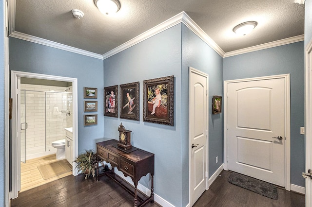 foyer entrance with dark wood-type flooring, crown molding, baseboards, and a textured ceiling