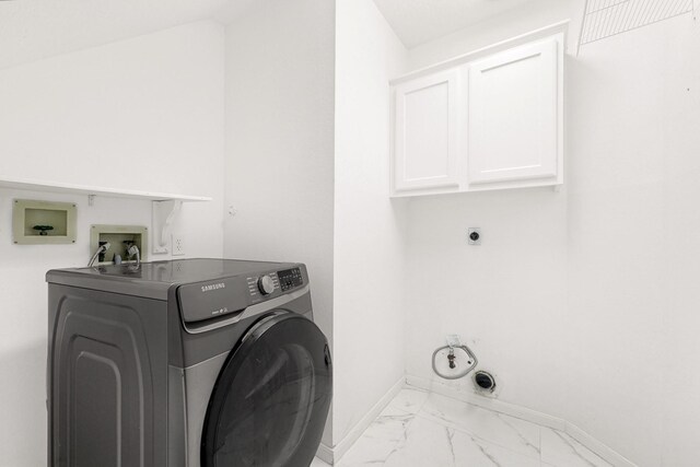 washroom with marble finish floor, baseboards, cabinet space, and washer / dryer