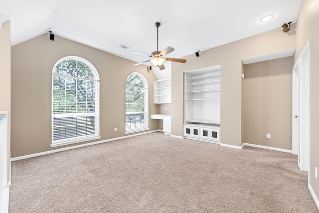 unfurnished living room featuring built in features, carpet flooring, a ceiling fan, visible vents, and lofted ceiling