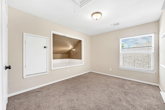 carpeted spare room with visible vents, baseboards, attic access, and a textured ceiling