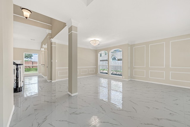 spare room with ornate columns, a decorative wall, marble finish floor, and ornamental molding