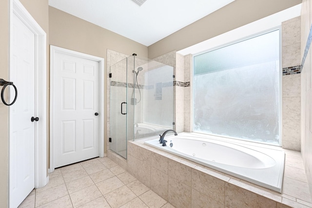 bathroom featuring tile patterned flooring, a bath, and a stall shower
