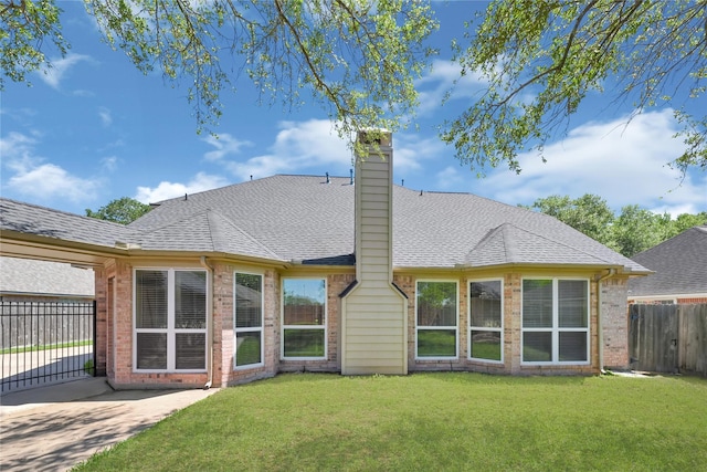 rear view of property featuring a shingled roof, a lawn, fence, brick siding, and driveway